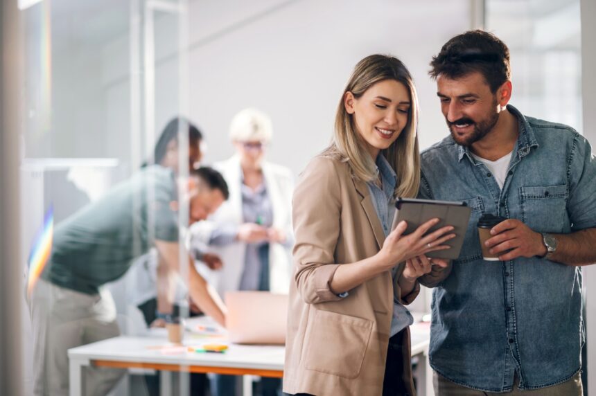 Two,Young,Businesspeople,Using,A,Digital,Tablet,While,Standing,In
